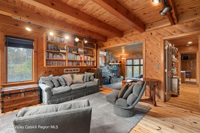 living room with beam ceiling, a wood stove, wooden ceiling, wood walls, and light hardwood / wood-style floors