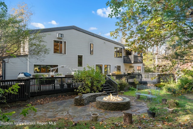 back of property featuring a balcony, an outdoor fire pit, a patio area, and a wooden deck