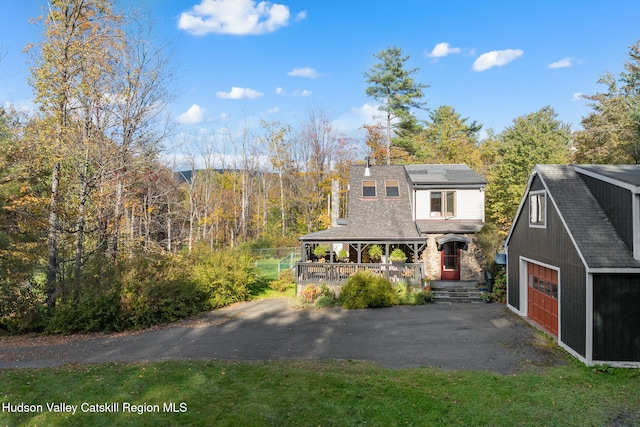 view of front of property featuring a porch, a garage, and an outdoor structure