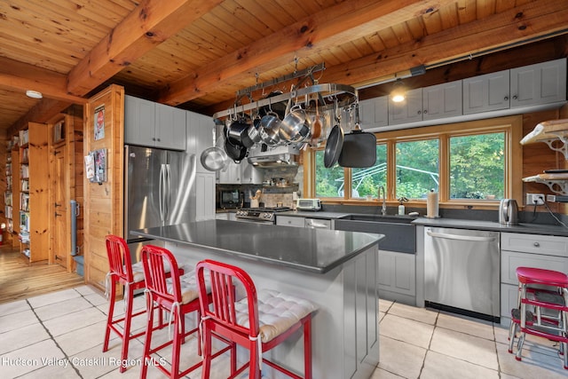 kitchen featuring light tile patterned flooring, sink, a kitchen island, wood ceiling, and stainless steel appliances