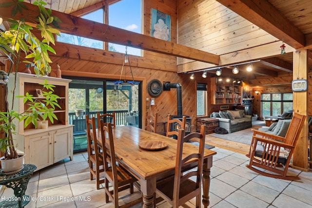 tiled dining area featuring a wood stove, wooden walls, rail lighting, and wood ceiling