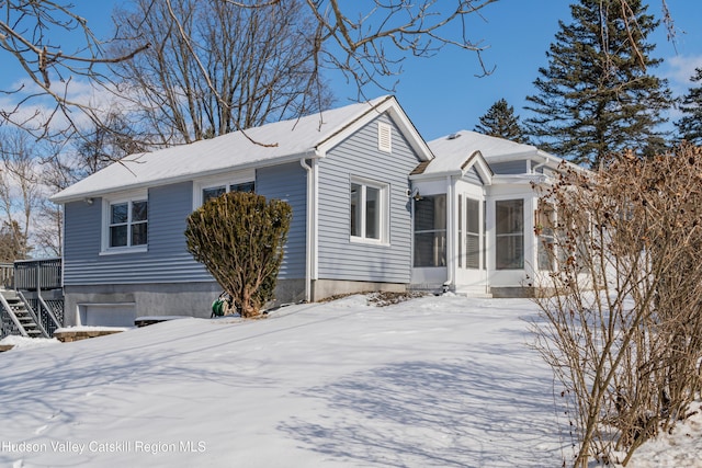 view of snow covered exterior featuring a garage and a sunroom