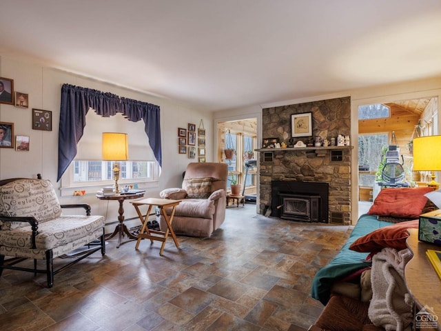 living area featuring plenty of natural light, stone tile flooring, a fireplace, and a baseboard radiator