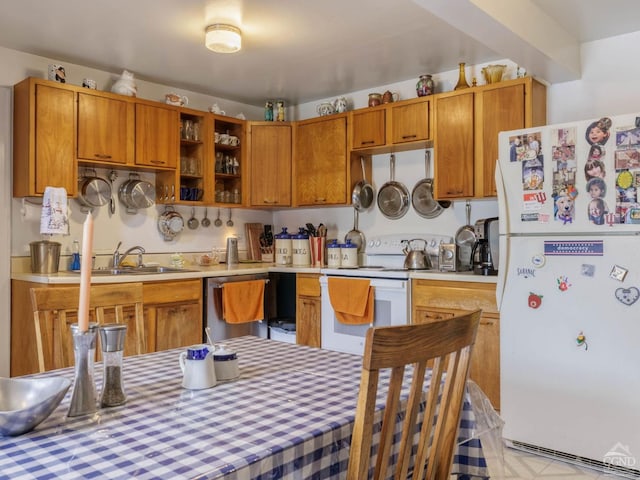 kitchen with white appliances, light countertops, a sink, and brown cabinetry