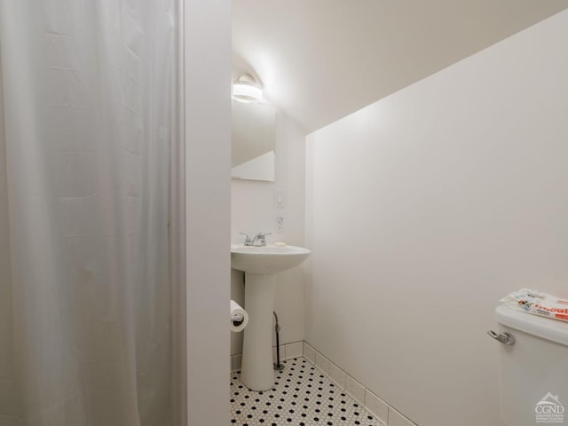 full bath with a shower with shower curtain, baseboards, and toilet