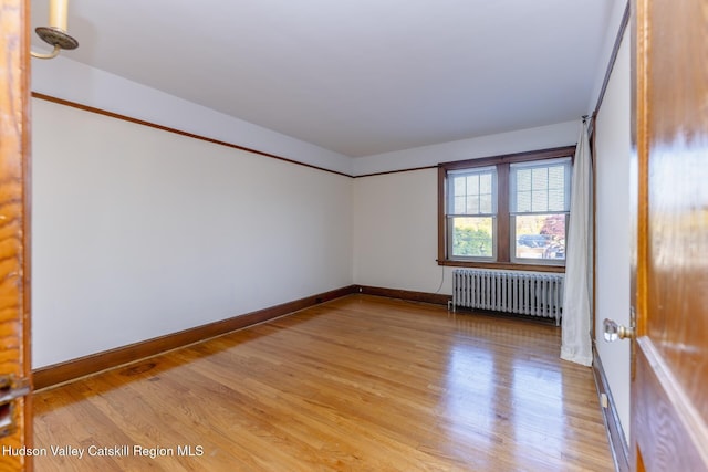 unfurnished room with light hardwood / wood-style flooring and radiator