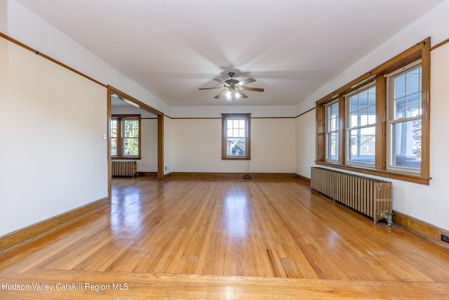 spare room with ceiling fan, light wood-type flooring, and radiator