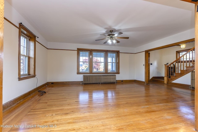 spare room featuring radiator heating unit, light wood-type flooring, and a wealth of natural light