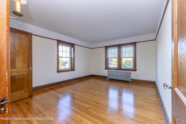 empty room featuring light wood-type flooring and radiator heating unit