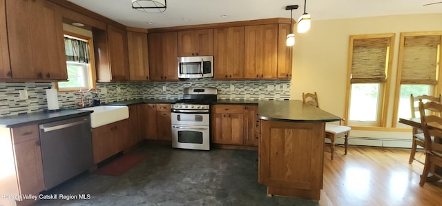273 E Conesville Rd, Conesville, NY 12076 - kitchen featuring appliances with stainless steel finishes, a peninsula, dark countertops, a baseboard heating unit, and brown cabinetry