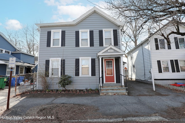 view of front facade featuring entry steps, driveway, and fence