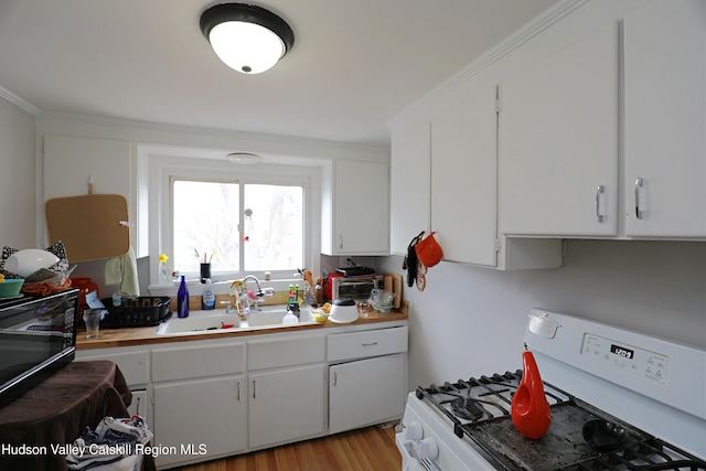 kitchen featuring a sink, white cabinetry, white gas range, and light wood finished floors