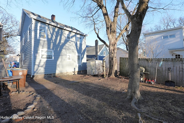 back of property with a chimney and fence