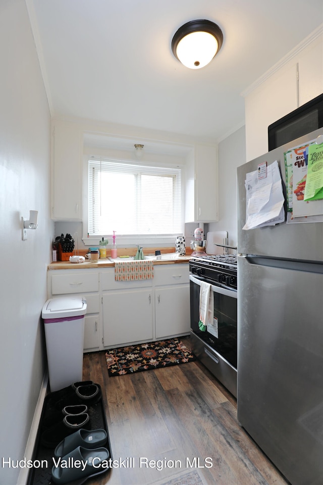 kitchen with freestanding refrigerator, dark wood-type flooring, white cabinets, gas stove, and black electric stovetop