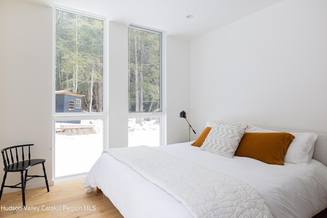 bedroom with floor to ceiling windows and light wood-style flooring