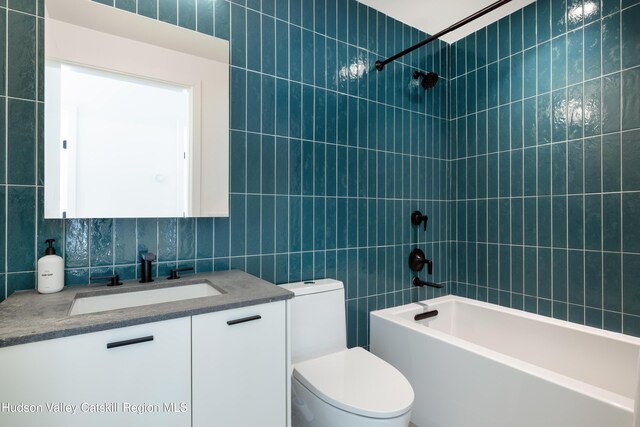 bathroom with tile walls, backsplash, toilet, vanity, and  shower combination