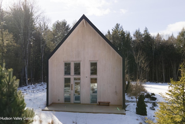 snow covered structure with an outbuilding