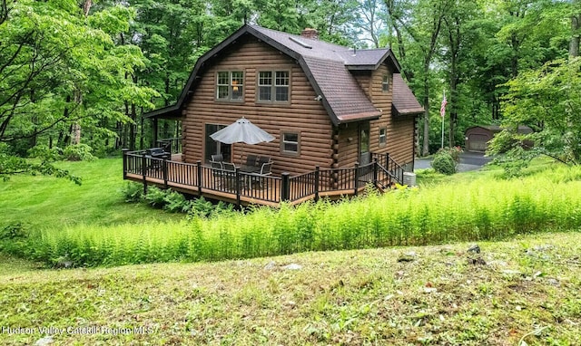 1206 Hollow Rd, Clinton, NY 12514 - rear view of property with a deck, log siding, a gambrel roof, a chimney, and a view of trees