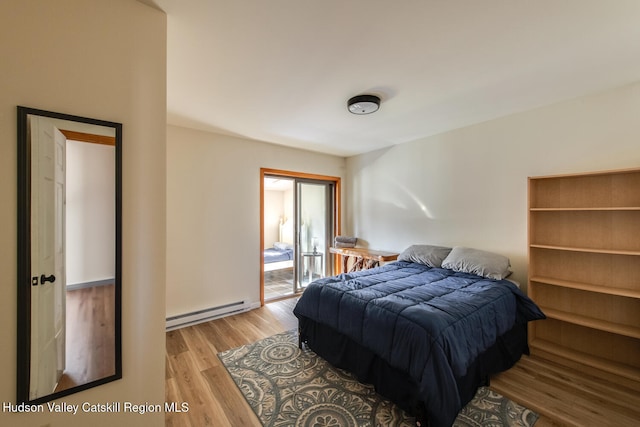 bedroom featuring light wood-type flooring and a baseboard heating unit