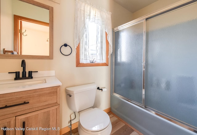 full bathroom featuring hardwood / wood-style flooring, toilet, combined bath / shower with glass door, and vanity