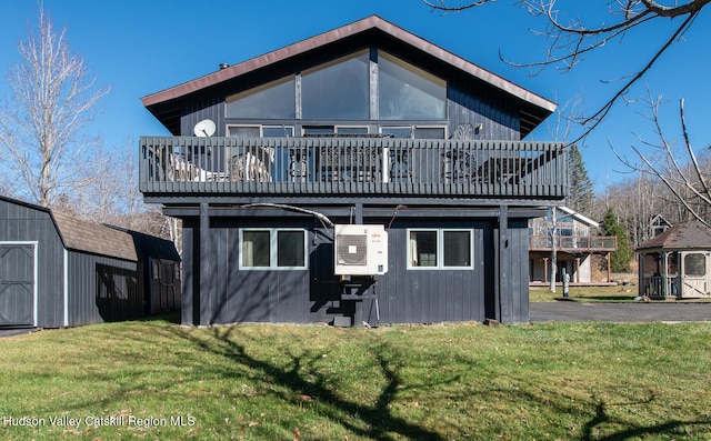 rear view of property with a yard, a deck, and a storage unit