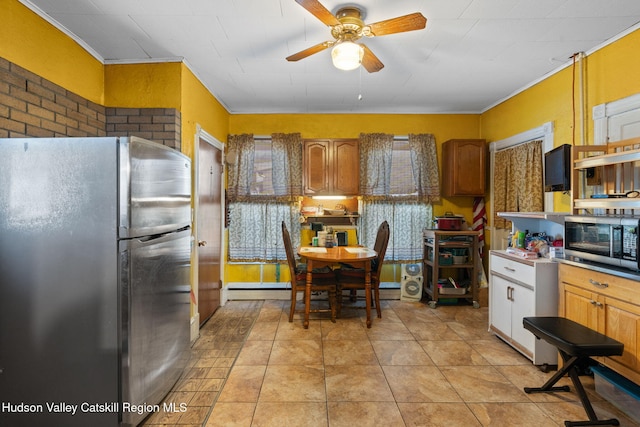 kitchen with light tile patterned flooring, crown molding, ceiling fan, stainless steel appliances, and a baseboard heating unit