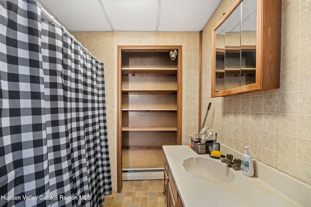 bathroom featuring tile walls, vanity, a paneled ceiling, and a baseboard radiator
