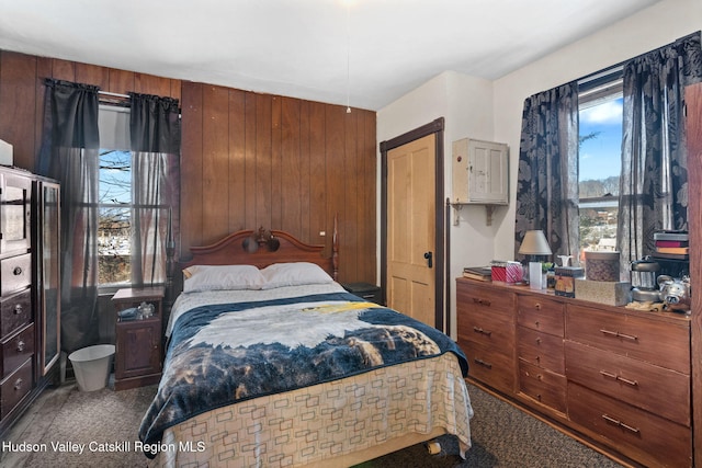 bedroom featuring carpet flooring and wood walls