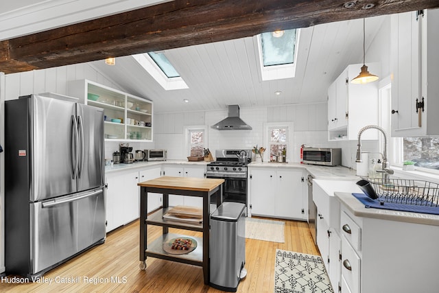 kitchen featuring pendant lighting, stainless steel appliances, light countertops, white cabinets, and wall chimney exhaust hood