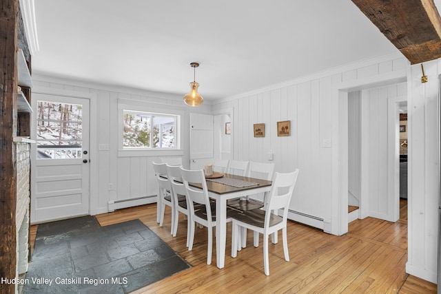 dining area with light wood finished floors, a baseboard radiator, and ornamental molding