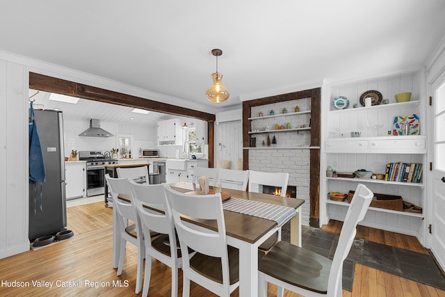 dining space with a brick fireplace and light wood-style flooring