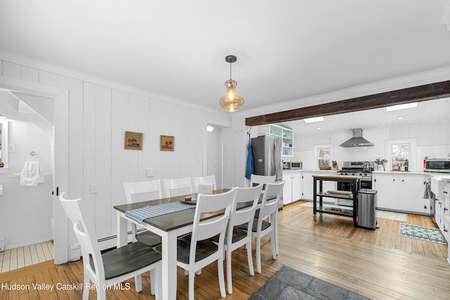 dining room featuring light wood-style flooring, beam ceiling, and crown molding