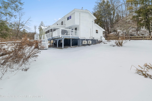 snow covered back of property with stairs and a wooden deck