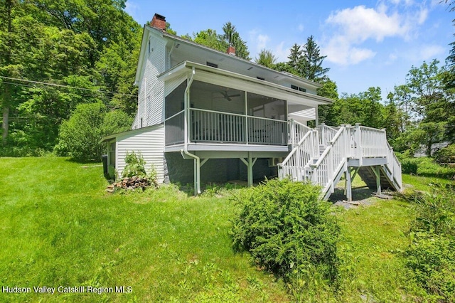 rear view of property with a chimney, a ceiling fan, stairway, a yard, and a sunroom