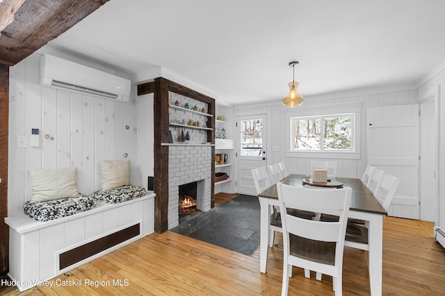 dining area featuring ornamental molding, a fireplace, a wall unit AC, and wood finished floors