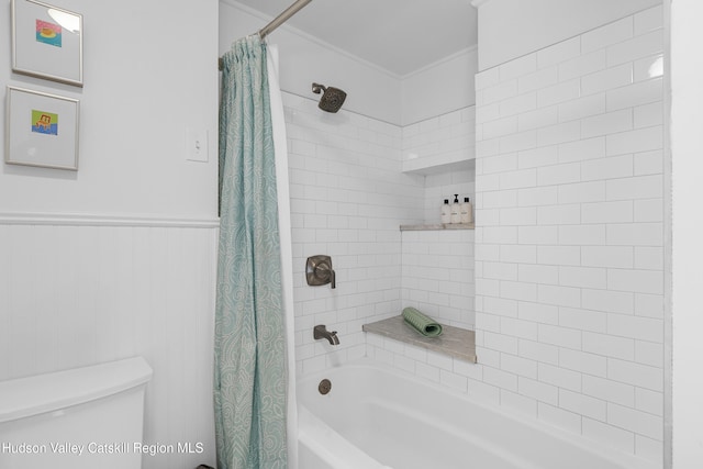 bathroom featuring wainscoting, shower / bath combo, and toilet