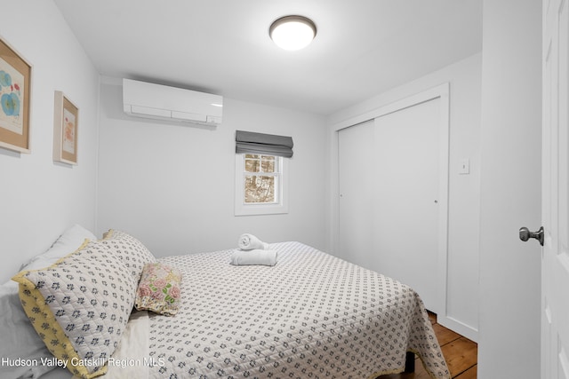 bedroom featuring a closet, a wall unit AC, and light wood-style floors