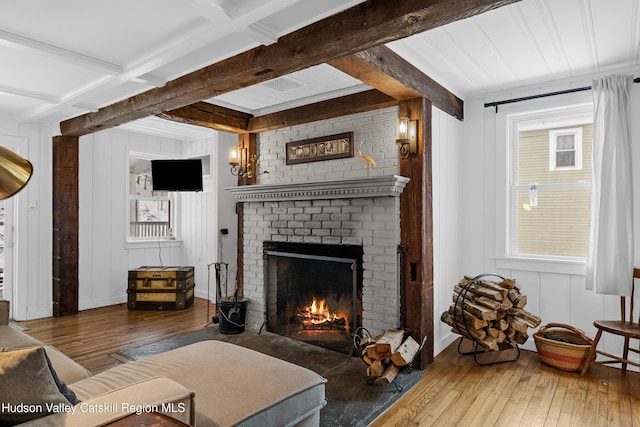 living area featuring a brick fireplace, wood finished floors, and beam ceiling