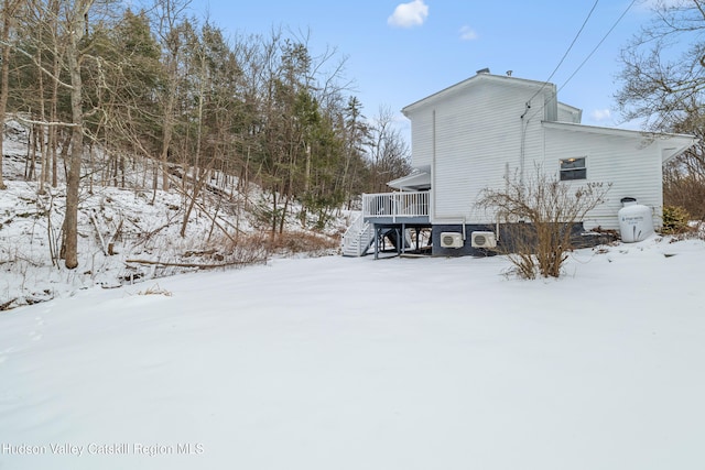 snow covered property with stairs and a deck