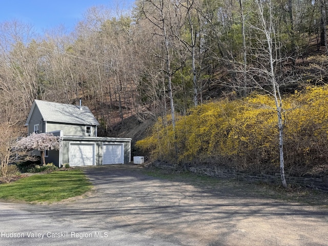 garage with aphalt driveway and a forest view