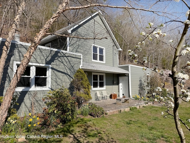 rear view of property with a lawn and a patio