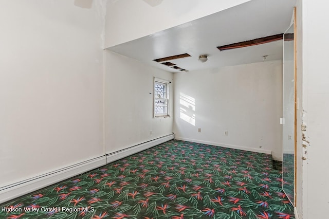 empty room with carpet, baseboards, and a baseboard heating unit