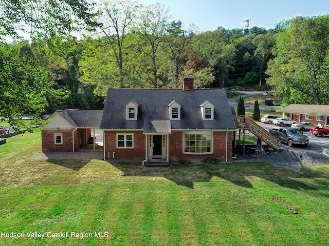 cape cod home featuring a chimney, stairs, a front lawn, roof with shingles, and brick siding