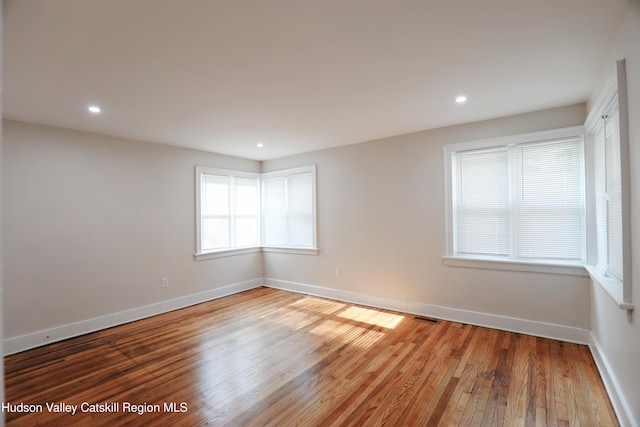 unfurnished room with recessed lighting, wood finished floors, visible vents, and baseboards