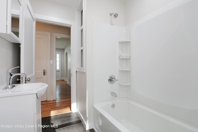 full bathroom with baseboards, vanity, wood finished floors, and shower / bathing tub combination
