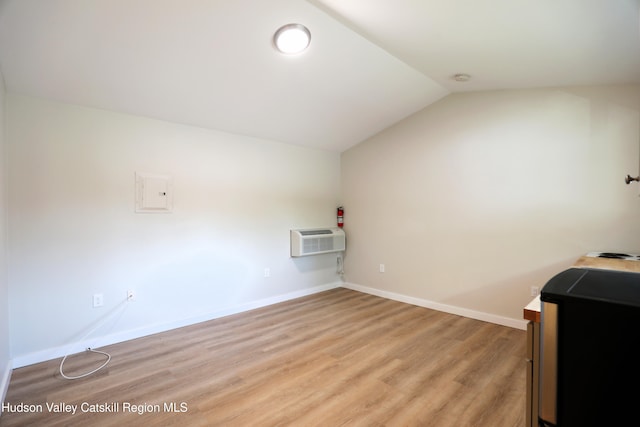interior space with a wall mounted air conditioner, lofted ceiling, baseboards, and light wood-style flooring