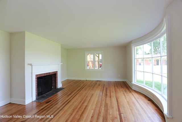 unfurnished living room featuring light wood finished floors, baseboards, and a fireplace