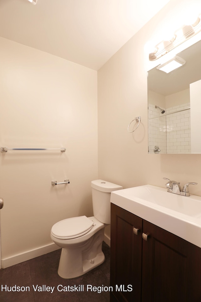 bathroom featuring vanity, walk in shower, baseboards, toilet, and tile patterned flooring