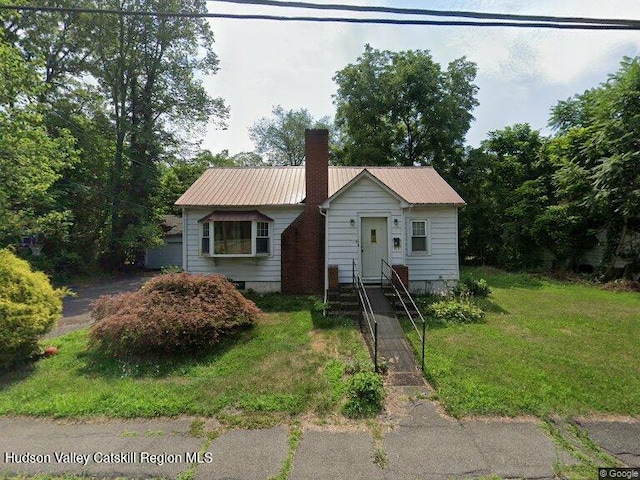 bungalow with a front yard, a chimney, and metal roof