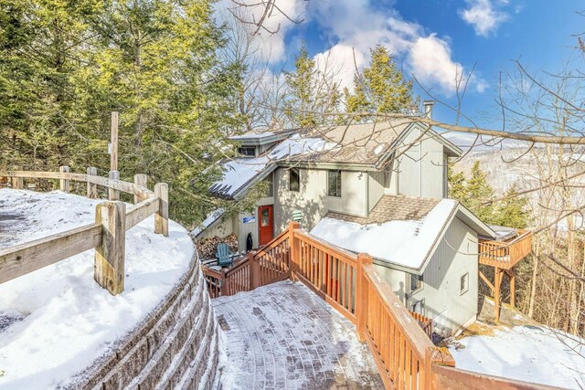 snow covered rear of property with a deck